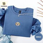 Indigo Blue crewneck sweatshirt folded with light jeans and dried twigs, embroidered with a mini Cavachon face in cream and apricot with a white muzzle