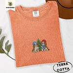 Terracotta Comfort Colors T-shirt embroidered with two Blenheim Cavalier King Charles Spaniels in knit beanies beside a little lit Christmas tree