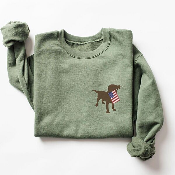 Military Green crewneck sweatshirt laid flat, embroidered with a brown Labrador holding a stars-and-stripes flag on the left chest