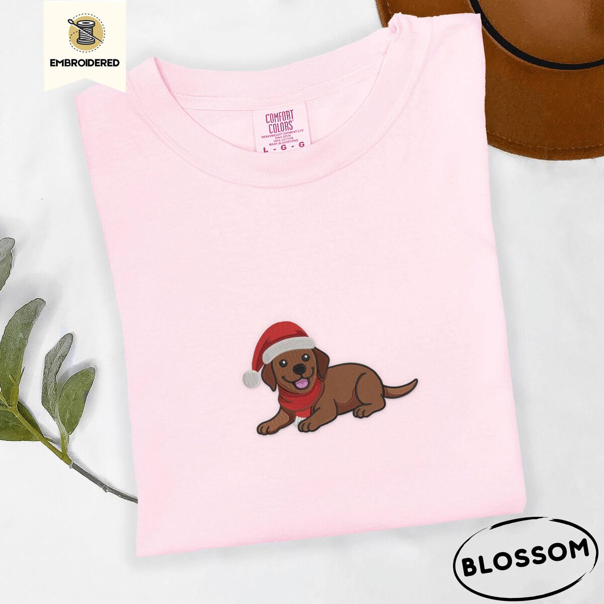Chocolate Lab Santa Hat Shirt – Blossom Blossom Comfort Colors T-shirt embroidered with a chocolate Labrador puppy lying down in a red Santa hat and a red knit scarf