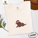 Ivory Comfort Colors T-shirt embroidered with a chocolate Labrador puppy lying down in a red Santa hat and a red knit scarf