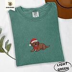 Light Green Comfort Colors T-shirt embroidered with a chocolate Labrador puppy lying down in a red Santa hat and a red knit scarf