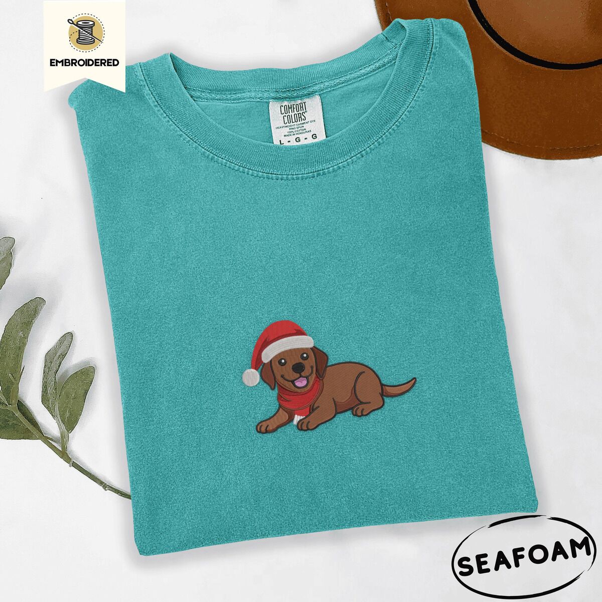 Chocolate Lab Santa Hat Shirt – Seafoam Seafoam Comfort Colors T-shirt embroidered with a chocolate Labrador puppy lying down in a red Santa hat and a red knit scarf