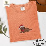 Terracotta Comfort Colors T-shirt embroidered with a chocolate Labrador puppy lying down in a red Santa hat and a red knit scarf