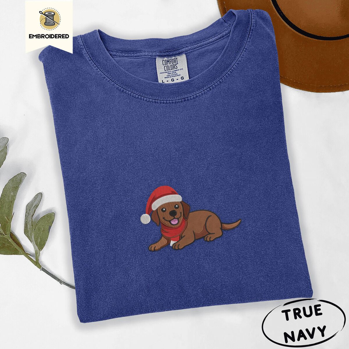 Chocolate Lab Santa Hat Shirt – True Navy True Navy Comfort Colors T-shirt embroidered with a chocolate Labrador puppy lying down in a red Santa hat and a red knit scarf