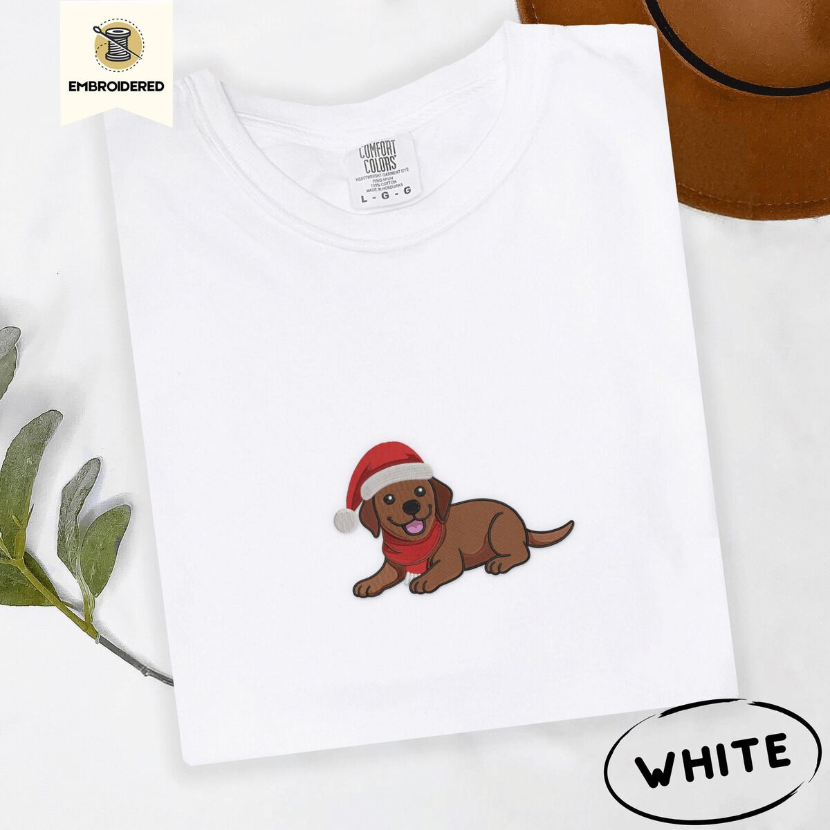 Chocolate Lab Santa Hat Shirt – White White Comfort Colors T-shirt embroidered with a chocolate Labrador puppy lying down in a red Santa hat and a red knit scarf