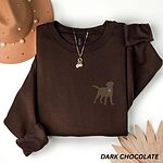 Dark Chocolate crewneck sweatshirt laid flat with a hat and a necklace, embroidered with a small chocolate brown Labrador silhouette in a blue collar and gold bone tag on the left chest