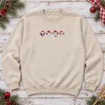 Sand Christmas cow crewneck laid flat with four embroidered Santa cows across the chest, pine sprigs and red ornaments