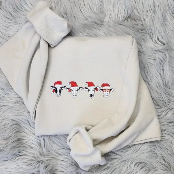 Christmas cow sweatshirt in Sand with four embroidered cow heads in red Santa hats, one with red bows and one in red sunglasses
