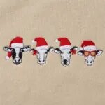Detail of the embroidered Christmas cows with red Santa hats, red bows and red sunglasses
