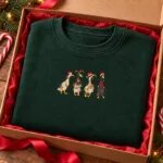 Christmas duck sweatshirt folded in a gift box with red tissue paper and candy canes