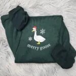 Christmas goose sweatshirt in Forest Green with a white goose in a Santa hat, snowflakes and the words merry goose