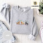Ash crewneck sweatshirt folded with denim shorts, white sneakers and a potted plant, embroidered with three horses in Santa hats, a red scarf and red leg wraps under turquoise snowflakes