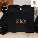 Black crewneck sweatshirt with a brown felt hat and dried bunny tail grass, embroidered with three horses in Santa hats, a red scarf and red leg wraps under turquoise snowflakes