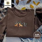 Dark Chocolate crewneck sweatshirt on a plaid flannel shirt with yellow autumn leaves and denim shorts, embroidered with three horses in Santa hats, a red scarf and red leg wraps under turquoise snowflakes