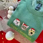 Christmas sweater with pet faces: heather green sweatshirt with two dogs and a tabby cat in Santa hats above Furry Christmas text