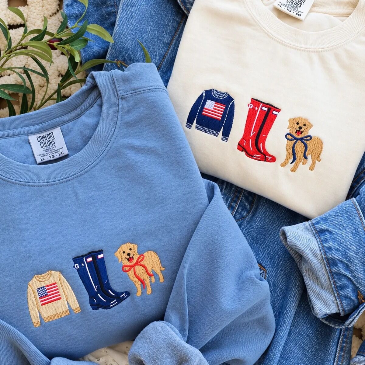 Coastal Icons Sweatshirt Blue Jean and Ivory Blue Jean and Ivory Comfort Colors sweatshirts on a denim jacket, one with a tan flag sweater, navy boots and a golden in a red bow, the other with a navy sweater, red boots and a navy bow