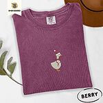Berry Comfort Colors T-shirt embroidered with a cream goose in a Santa hat with a red ribbon bow at its neck
