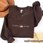 Dark Chocolate crewneck sweatshirt laid flat with a felt hat and a necklace, embroidered with CORGI MOM and a fluffy corgi rear with two paws