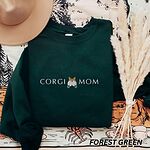 Forest Green crewneck sweatshirt laid flat with a felt hat and dried pampas grass, embroidered with CORGI MOM in light thread around a corgi butt