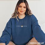 Smiling woman in an Indigo Blue crewneck sweatshirt embroidered with CORGI MOM and a corgi butt between the words