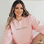 Smiling woman in a Light Pink crewneck sweatshirt embroidered with CORGI MOM and a corgi butt with two little paws
