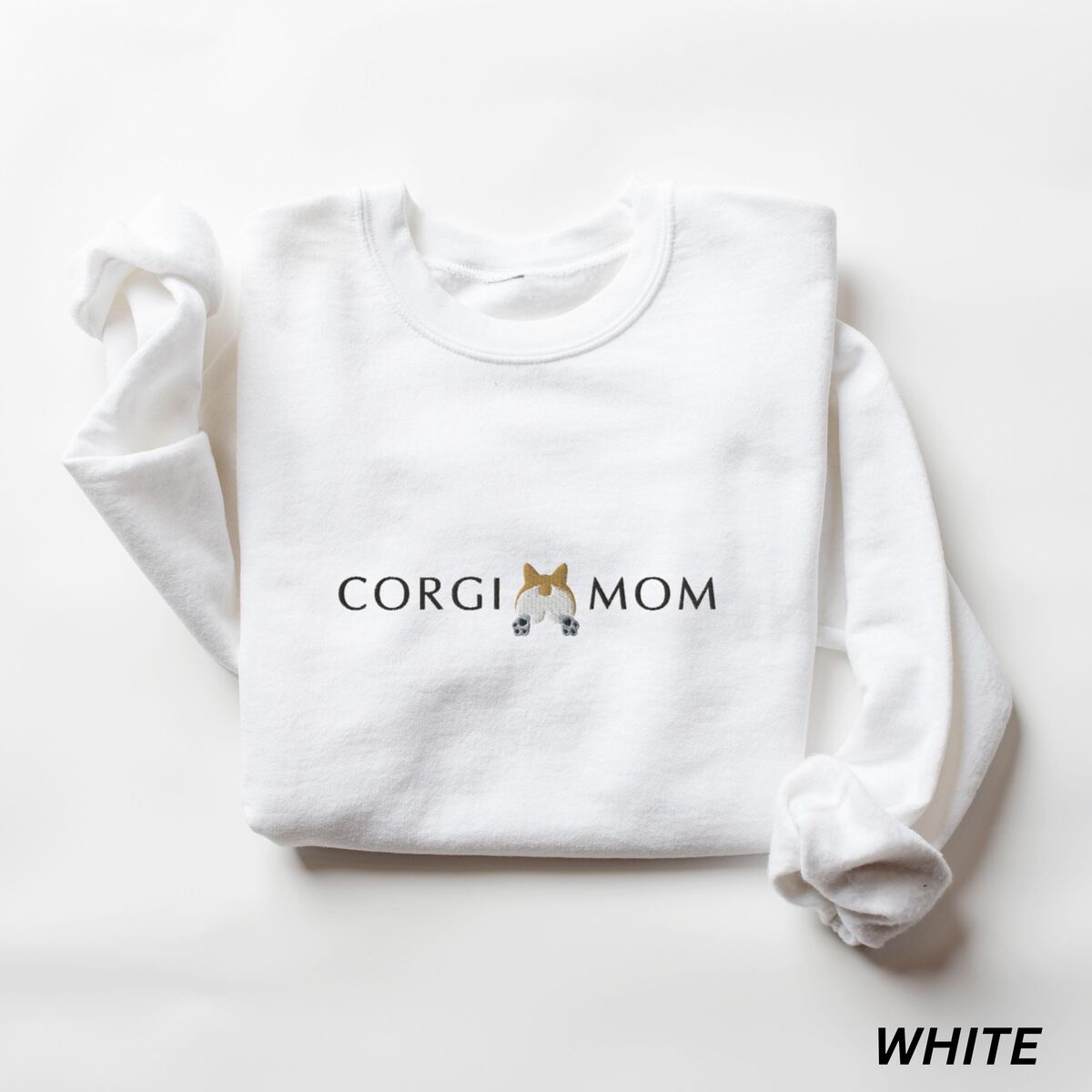 Corgi Butt Sweatshirt - White White crewneck sweatshirt laid flat on white, embroidered with CORGI MOM in dark thread and a fluffy corgi butt between the words