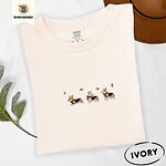 Ivory Comfort Colors T-shirt embroidered with three tricolor corgis in red knit scarves among sprigs of holly