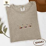 Khaki Comfort Colors T-shirt embroidered with three tricolor corgis in red knit scarves among sprigs of holly