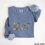 Blue Jean crewneck sweatshirt laid flat with rolled sleeves, embroidered with four corgis under a crescent moon with bats, gold sparkles and a jack-o'-lantern