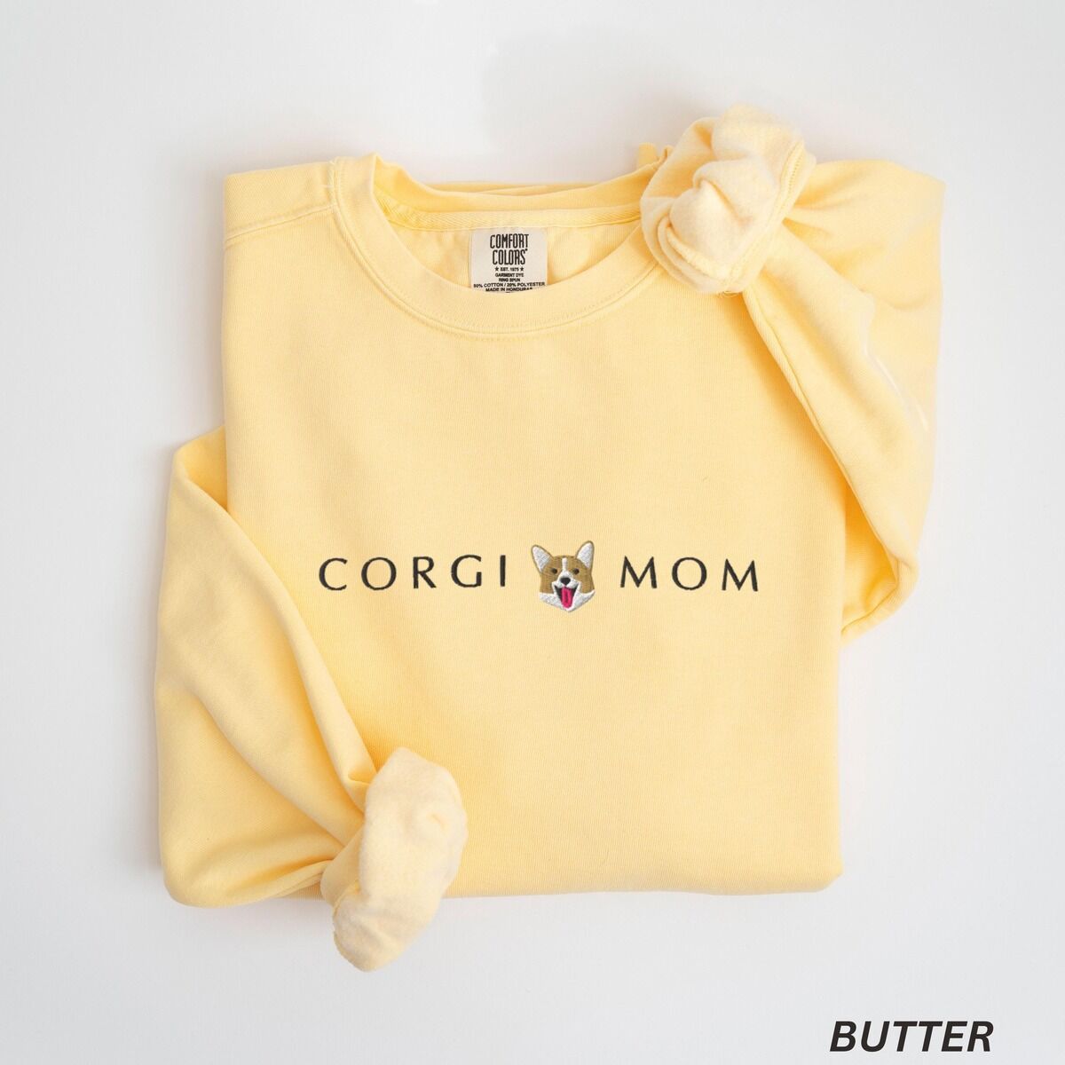 Corgi Mom Sweatshirt – Butter Butter crewneck sweatshirt laid flat on white, embroidered with CORGI MOM in dark thread and a red and white corgi face with its tongue out