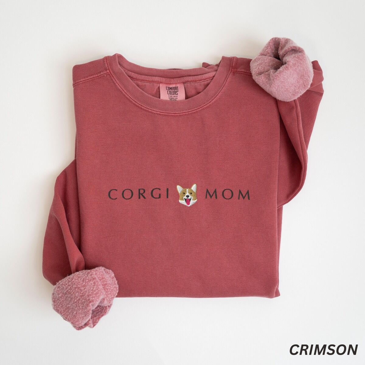 Corgi Mom Sweatshirt – Crimson Crimson crewneck sweatshirt laid flat on white, embroidered with CORGI MOM and a small red and white corgi face
