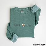 Light Green crewneck sweatshirt laid flat on white, embroidered with CORGI MOM and a corgi face with a pink tongue