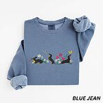 Blue Jean crewneck sweatshirt laid flat on white, embroidered with three black and tan dachshunds playing among white daisies and pink spring flowers, with two bees and a yellow butterfly, across the chest