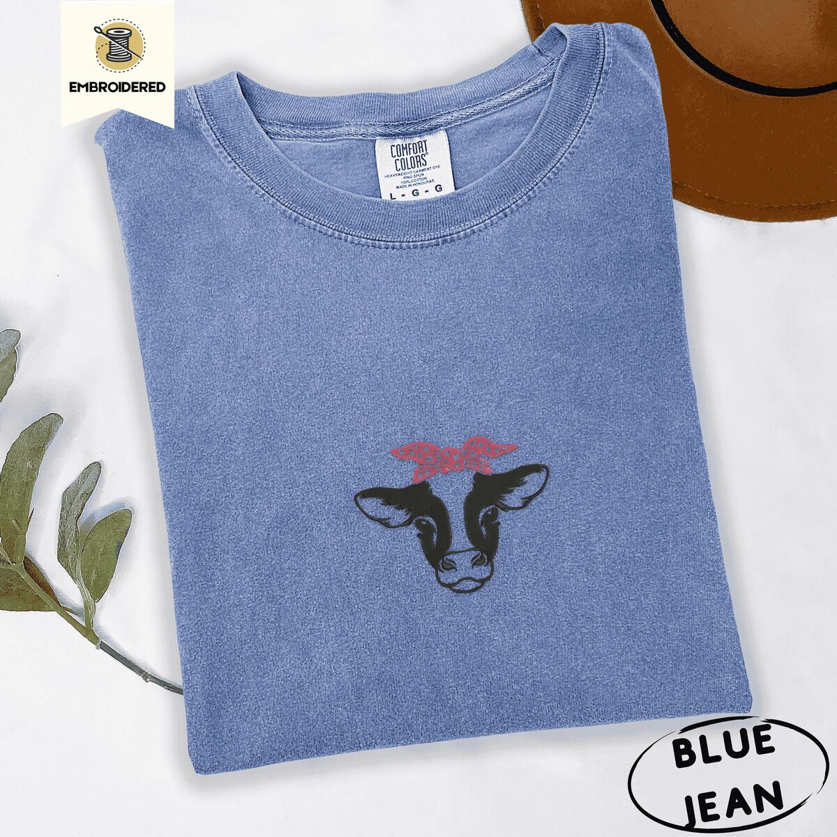 Cow Bandana Shirt – Blue Jean Blue Jean Comfort Colors T-shirt embroidered with a black and white cow head wearing a pink heart bandana tied in a bow