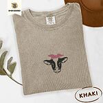 Khaki Comfort Colors T-shirt embroidered with a black and white cow head wearing a pink heart bandana tied in a bow