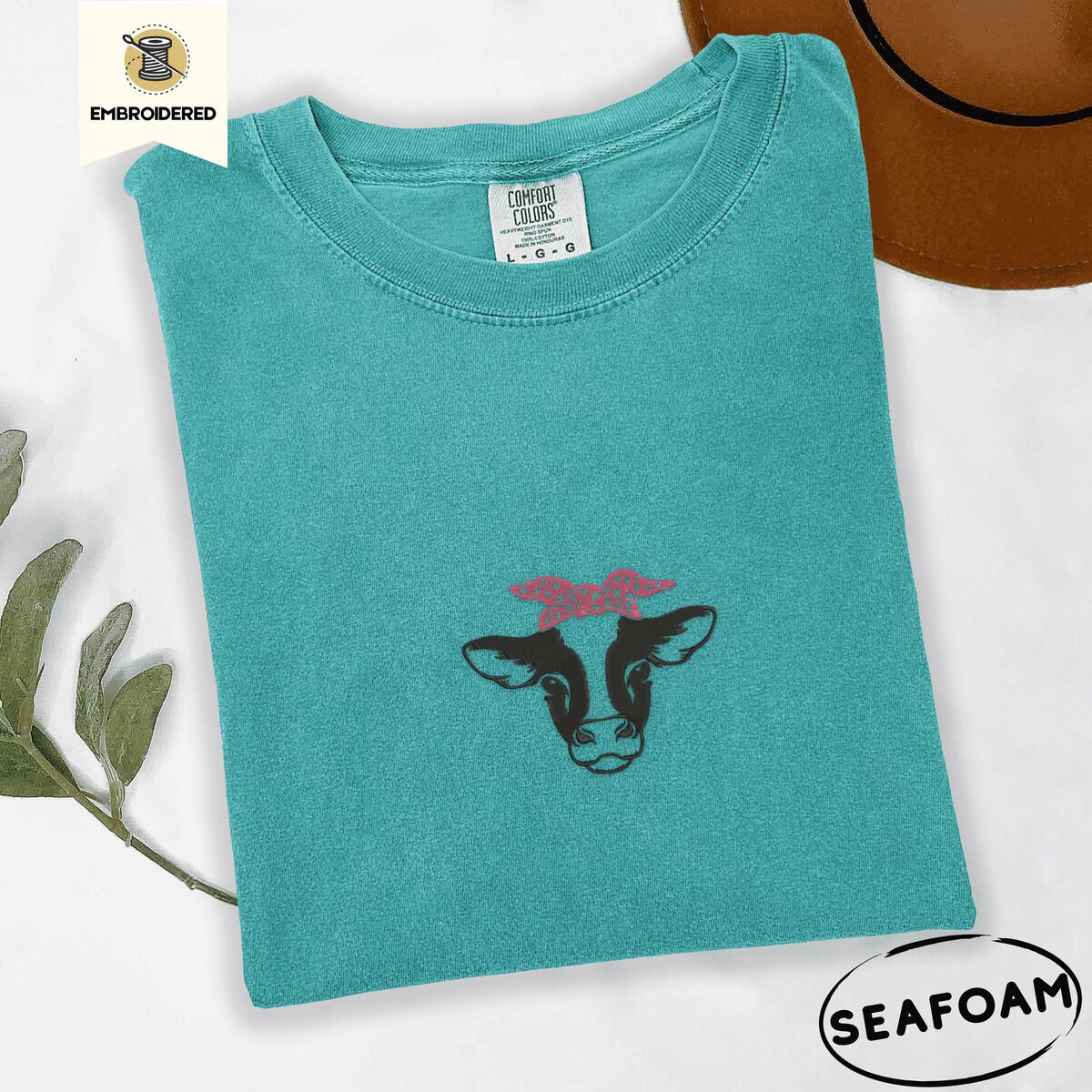 Cow Bandana Shirt – Seafoam Seafoam Comfort Colors T-shirt embroidered with a black and white cow head wearing a pink heart bandana tied in a bow