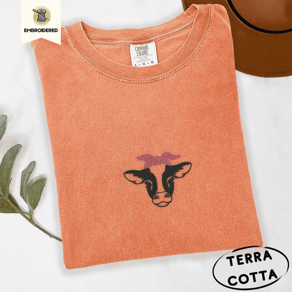 Cow Bandana Shirt – Terracotta Terracotta Comfort Colors T-shirt embroidered with a black and white cow head wearing a pink heart bandana tied in a bow