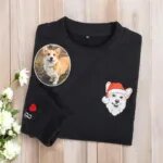 Black sweatshirt with an embroidered corgi portrait in a Santa hat and an initial with a red heart on the sleeve