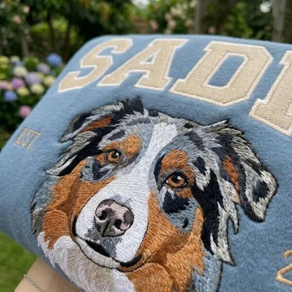 Close-up of the embroidered Australian Shepherd portrait and beige varsity letters on the custom dog crewneck