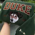 Green custom dog crewneck with the name DUKE in varsity letters, an embroidered dog face, EST 2023 and a sleeve icon
