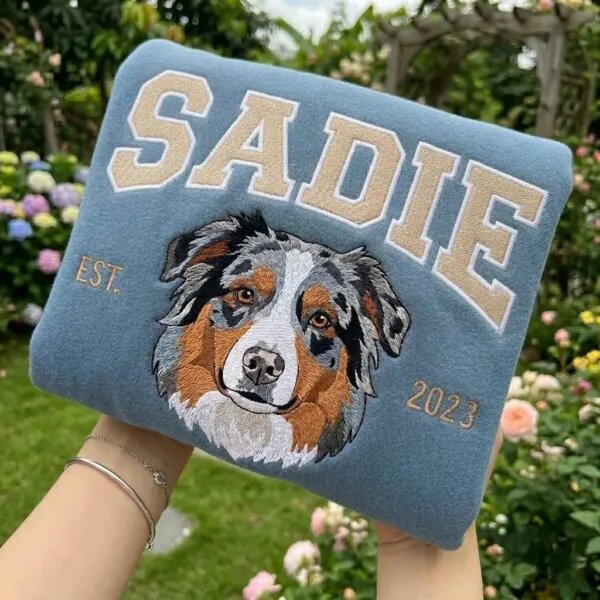 Custom dog crewneck in blue with an embroidered Australian Shepherd face, the name SADIE in varsity letters and EST 2023
