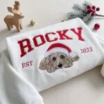 White Christmas sweatshirt with a doodle portrait in a Santa hat under arched varsity name lettering