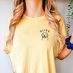 Woman in a Butter T-shirt embroidered with a line art golden retriever face and the name OLIVE on the left chest