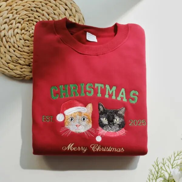 Custom pet Christmas sweatshirt in red with two embroidered cat portraits in Santa hats, green CHRISTMAS letters, EST 2025 and Merry Christmas script