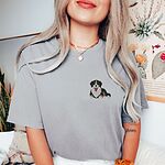 Woman in a Grey T-shirt embroidered with a small tricolor Bernese mountain dog puppy lying down on the left chest