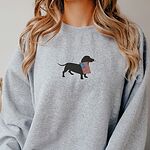 Woman in a sport grey crewneck sweatshirt with a dachshund silhouette and American flag on the chest