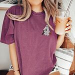 Woman holding an iced coffee in a Berry T-shirt embroidered on the left chest with a ghost sipping iced coffee, a black and tan dachshund and a jack-o'-lantern pail