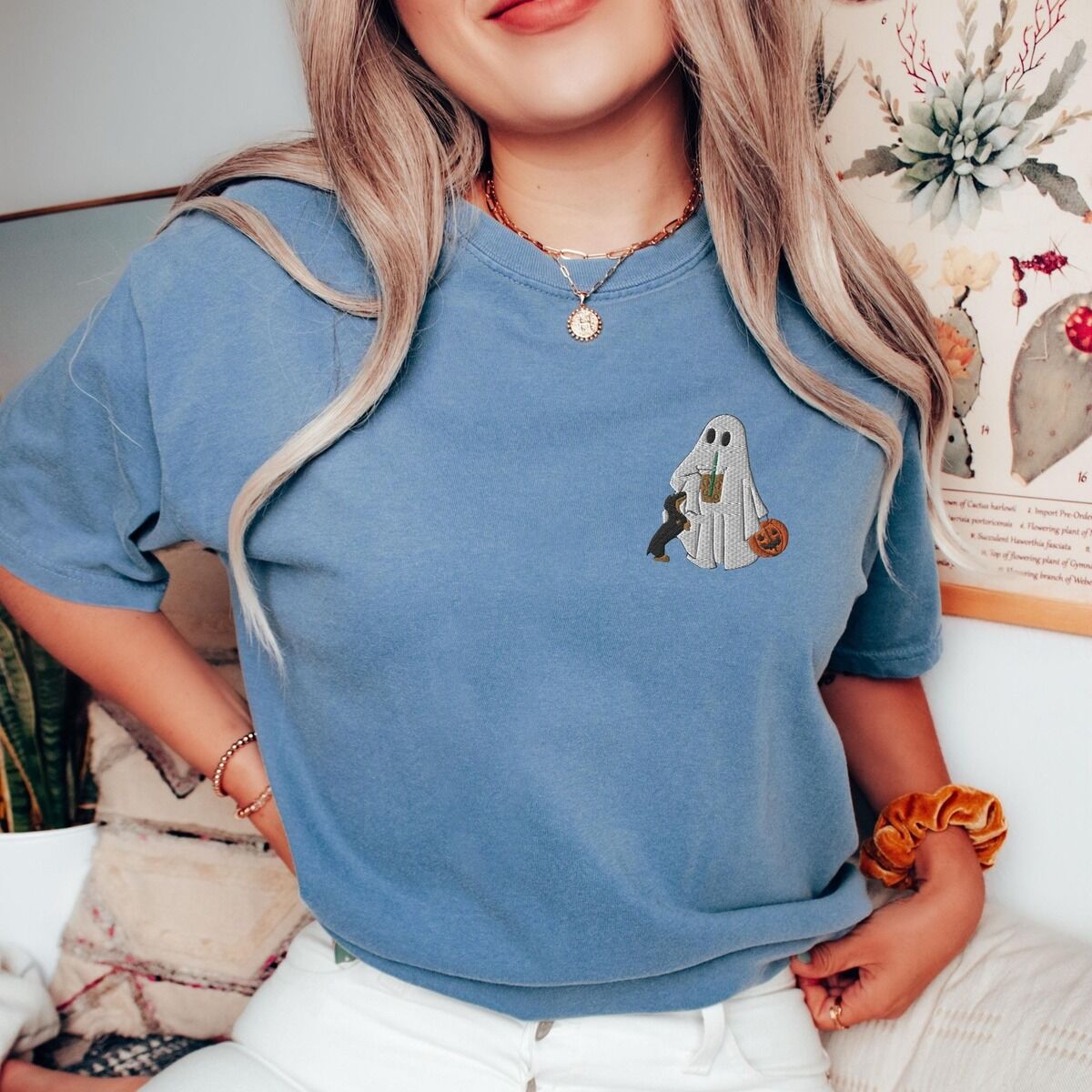 Dachshund Ghost Coffee Shirt – Blue Jean Woman in a Blue Jean T-shirt embroidered on the left chest with a ghost sipping iced coffee, a black and tan dachshund and a jack-o'-lantern pail