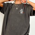 Woman in an oversized Pepper T-shirt embroidered on the left chest with a ghost sipping iced coffee, a black and tan dachshund and a jack-o'-lantern pail